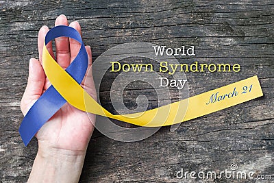 World down syndrome day WDSD March 21 Blue yellow awareness ribbon on helping hand for raising support on patient Stock Photo