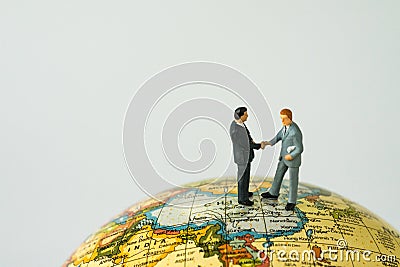 World leaders agreement hand shake teamwork concept with miniature business leaders hand shaking standing on globe map with copy Stock Photo