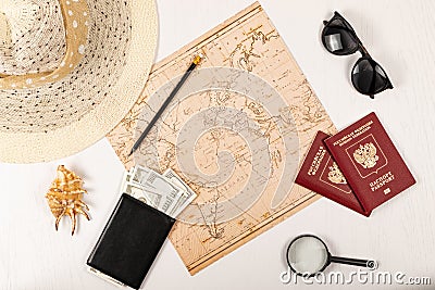 Map, pencil, two passports, sunglasses, shell, black wallet with money and a straw hat on a white wooden table. inscription - pass Stock Photo