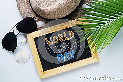 World Tourism Day Typography. Sunglasses, Fedora Hat, Palm Leaf, Sea Shells Background. Stock Photo