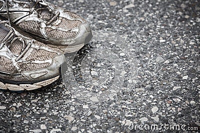 Worn, dirty, smelly and old running shoes on a tarmac road Stock Photo