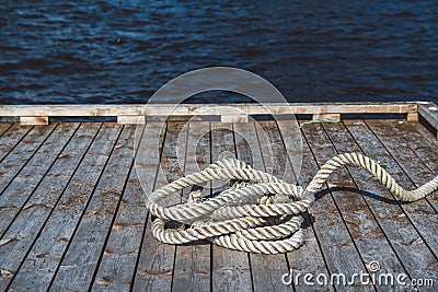 Worn out thick mooring rope on wooden pier. Can use as banner. Place for text or advertising Stock Photo