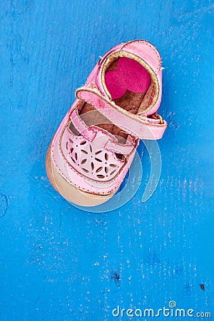 Worn pink children shoe on blue wooden background Stock Photo