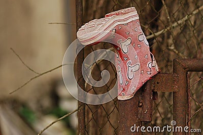 Worn pink with hearts girl`s boot with a hole placed on the gate post Stock Photo