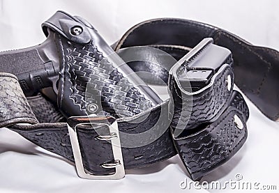 A worn police duty belt with a black pistol and two pistol magazine case wrapped up Stock Photo