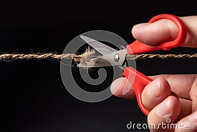 Worn rope ready to break, with scissors on black background Stock Photo