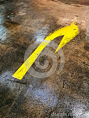 Worn Yellow Turn Right Sign on Wet Car Park Floor Stock Photo