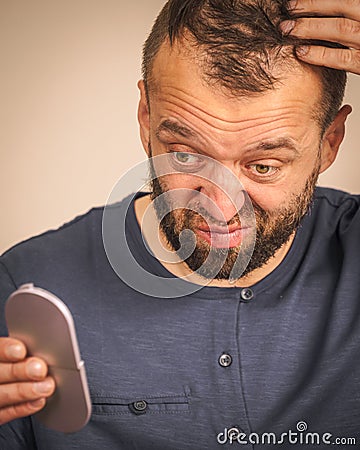 Worried man looking at little mirror Stock Photo