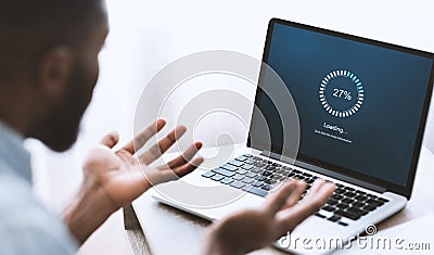 Worried african american man looking at laptop with loading screen Stock Photo