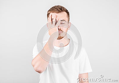 Worried American man covering face with both hands, looking at camera through his fingers Stock Photo