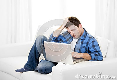 Worried Attractive man with computer sitting on couch Stock Photo