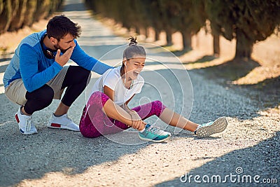 Worried beardy male with a hand on his mouth encouraging young female with sport injure Stock Photo