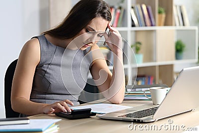 Worried bookkeeper looking at calculator at homeoffice Stock Photo
