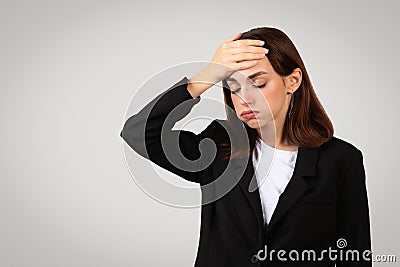 Worried businesswoman in a sleek black suit with her hand on her forehead displaying a gesture of forgetfulness Stock Photo