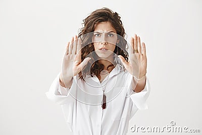 Worried and confident caucasian woman showing stop or do not come closer gesture with hands, frowning and expressing Stock Photo
