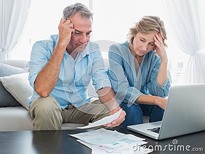 Worried couple paying their bills online with laptop Stock Photo