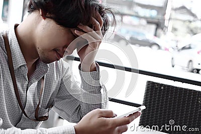 Worried depressed young Asian businessman looking mobile smart phone. Anxiety business concept. Stock Photo