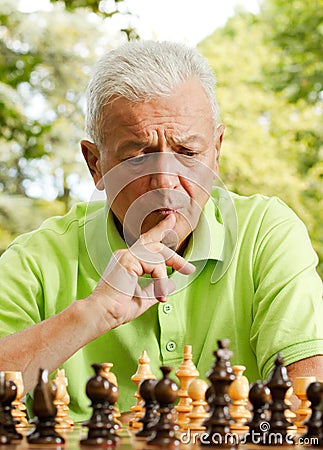 Worried elderly man playing chess outdoors Stock Photo