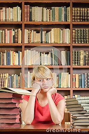 Worried female student in library with elbows on the table Stock Photo
