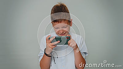 Worried funny addicted toddler boy enthusiastically playing drive racing video game on mobile phone Stock Photo