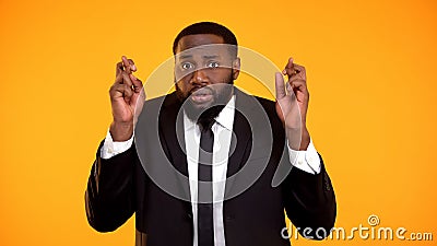 Worried funny superstitious afro-american man in suit crossing fingers interview Stock Photo