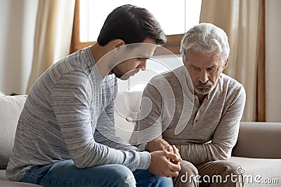 Worried grownup son supporting stressed unhealthy frustrated older dad. Stock Photo