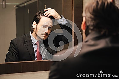 Worried Hispanic Business Man Looking At Hairline In Office Restrooms Stock Photo