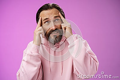 Worried intense disturbed mature male writer cannot create idea standing pressured touch forehead frowning look up Stock Photo