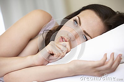 Worried Looking Young Woman On Bed Stock Photo