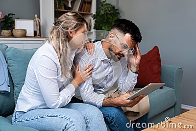 Worried man and woman husband and wife business owners looking tablet statistics feeling disappointed bank account negative Stock Photo