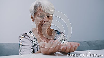 Worried mature gray haired woman holding pills in her hands Stock Photo