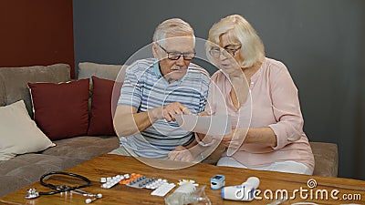 Senior couple looking at medicine prescription, pills, tablets at home. Coronavirus lockdown Stock Photo