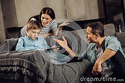 Worried parents yelling at their son for binge-playing Stock Photo