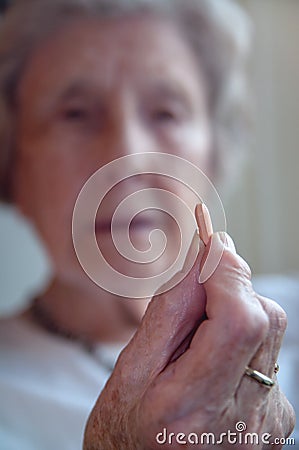 Sad senior woman taking pill Stock Photo