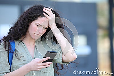 Worried student complaining checking cell phone Stock Photo