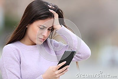 Worried teen checking bad news on smart phone Stock Photo