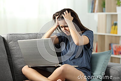 Worried teen reading bad news online at home Stock Photo