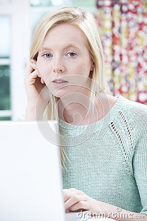 Worried Teenage Girl Using Laptop At Home Stock Photo