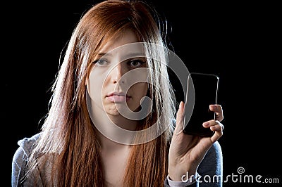 Worried teenager holding mobile phone as internet cyber bullying stalked victim abused Stock Photo