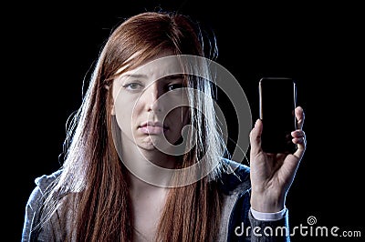 Worried teenager holding mobile phone as internet cyber bullying stalked victim abused Stock Photo