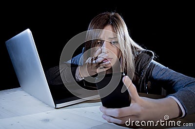 Worried teenager using mobile phone and computer as internet cyber bullying stalked victim abused Stock Photo