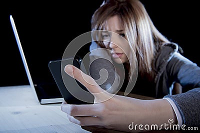 Worried teenager using mobile phone and computer as internet cyber bullying stalked victim abused Stock Photo