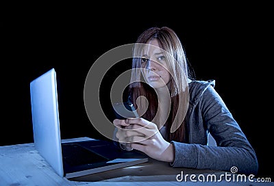 Worried teenager using mobile phone and computer as internet cyber bullying stalked victim abused Stock Photo