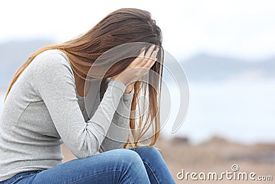 Worried teenager woman on the beach in winter Stock Photo