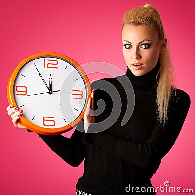 Worried woman with big orange clock gesturing delay, rush, nervous, stress because of lack of time. Stock Photo