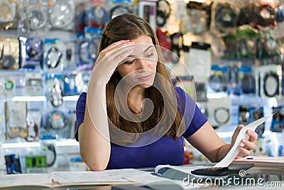 Worried Woman Checking Bills And Invoices In Computer Shop Stock Photo