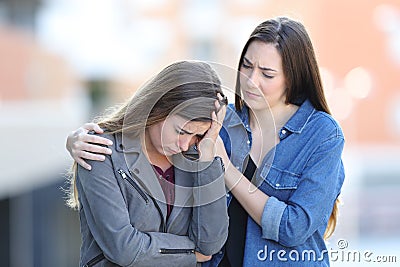 Worried woman comforting her sad friend in the street Stock Photo