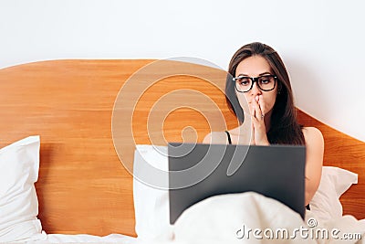 Worried Woman Looking at Laptop Sitting in Bed Stock Photo