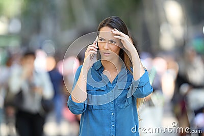 Worried woman talks on the phone in the street Stock Photo