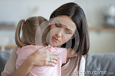 Worried young foster mother comforting embracing adopted child daughter Stock Photo